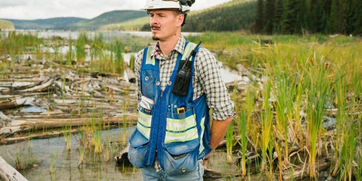 Un ingeniero ambiental con casco y chaleco trabajando en un sitio de ingeniería ambiental.