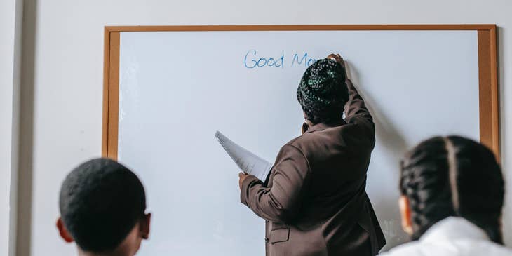 English teacher starts the class by writing something on the board for the students to read