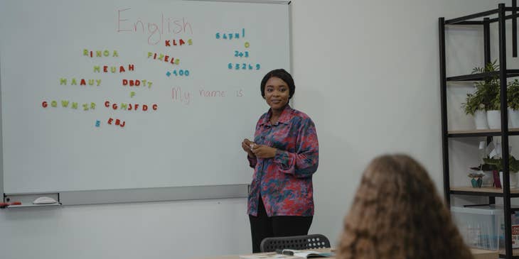 High School English Teacher looks at a student while teaching Spelling using magnetic alphabets