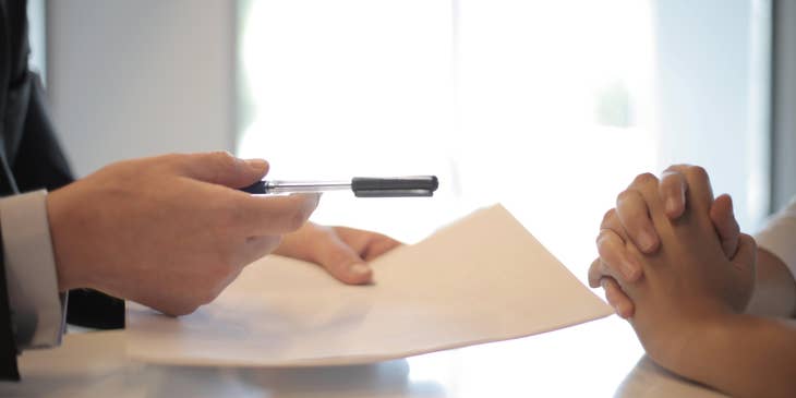 An Immigration Consultant handing a pen and a paper to a client.
