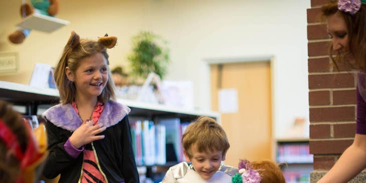 Kindergarten teacher assisting one of her students while wearing their costumes