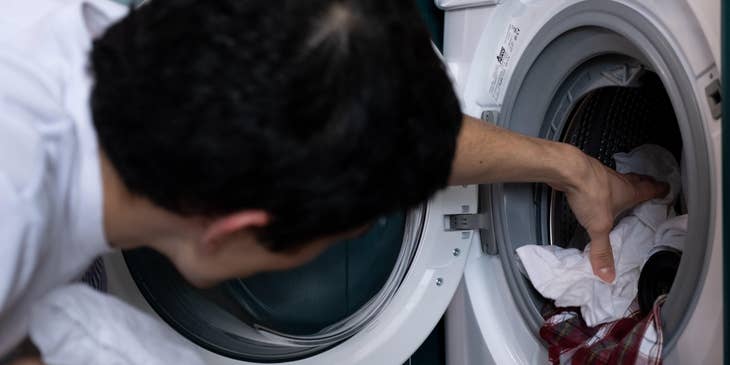 A laundry attendant taking out clothes from the washing machine.