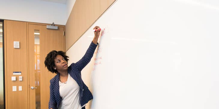 Lecturer discussing new learning platform while writing on a whiteboard