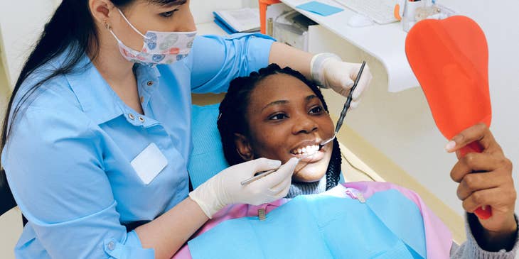 Periodontist shows a patient results after dental treatment using a mirror