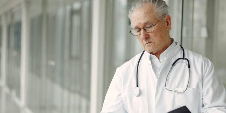 Physician reads clinical history while waiting for the patient outside his office