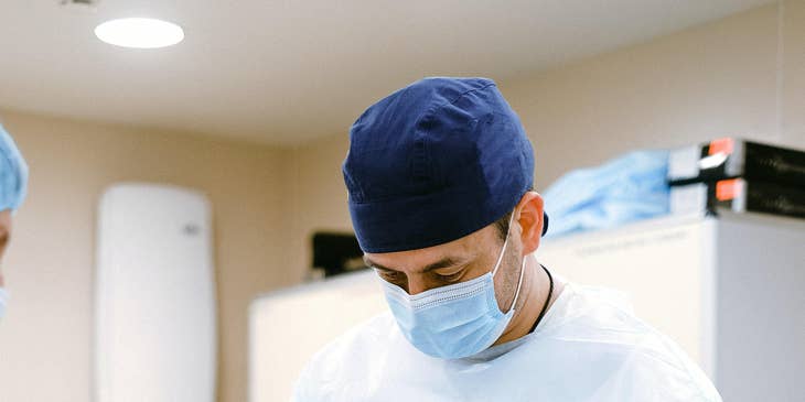 Plastic surgeon cutting a surgical thread as he finishes the operation.