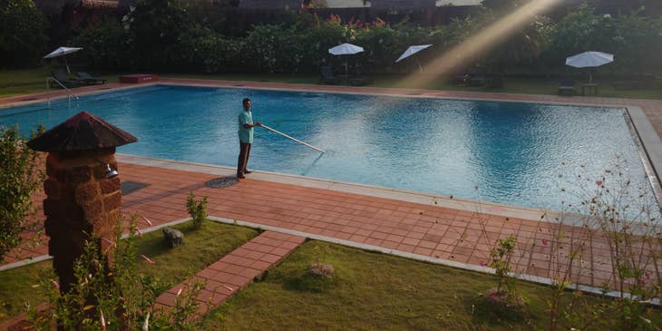 A pool attendant cleaning a pool on a sunny day.