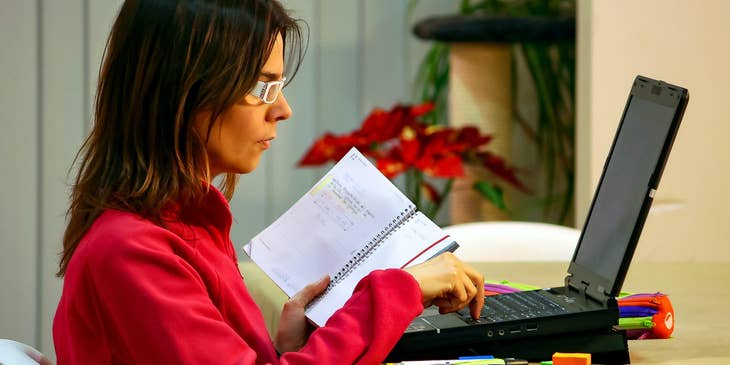 Practice administrator monitors budget and finances on her computer while checking on her notebook.