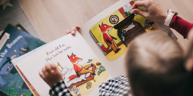 Preschool teacher reading an interactive storybook to a toddler