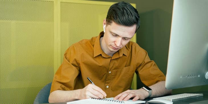 Registrar wearing an earphone writing admin tasks in a notebook as instructed by a senior staff over the phone