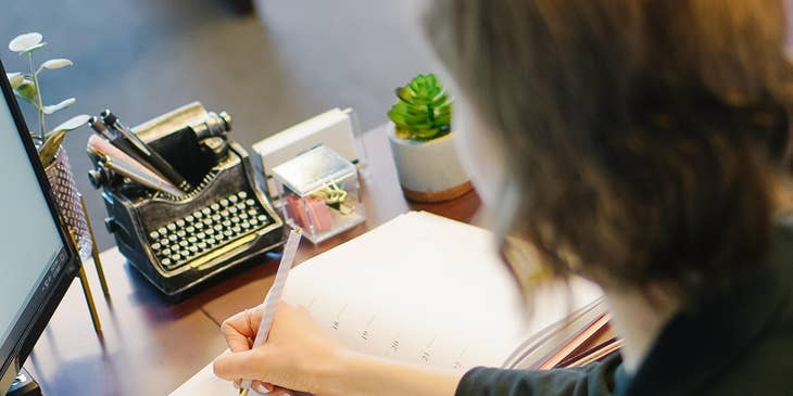 A female reservation agent writing on a notebook.