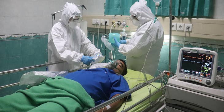 Respiratory care practitioner monitors a patient's condition with a colleague in a protective suit