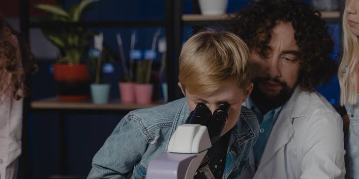 Science teacher conduct new experiments with a group of students using a microscope