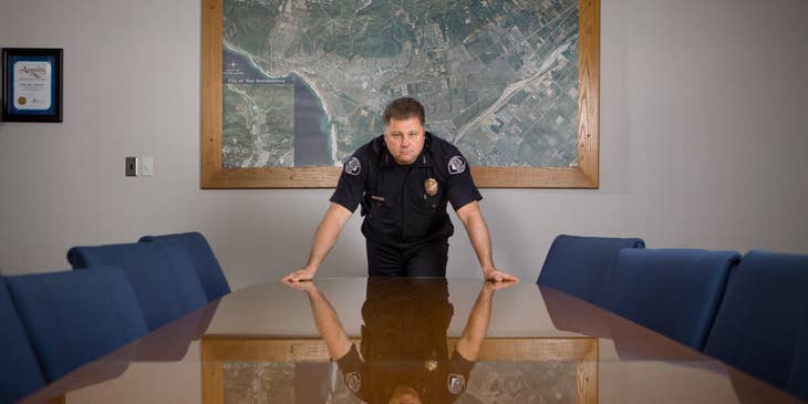 Security officer in a black uniform standing behind a conference table