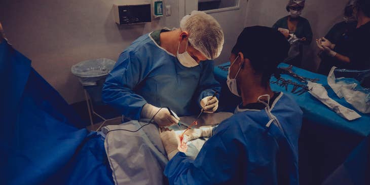 Surgical assistant holds the patient's body while the surgeon was applying sutures during the operation