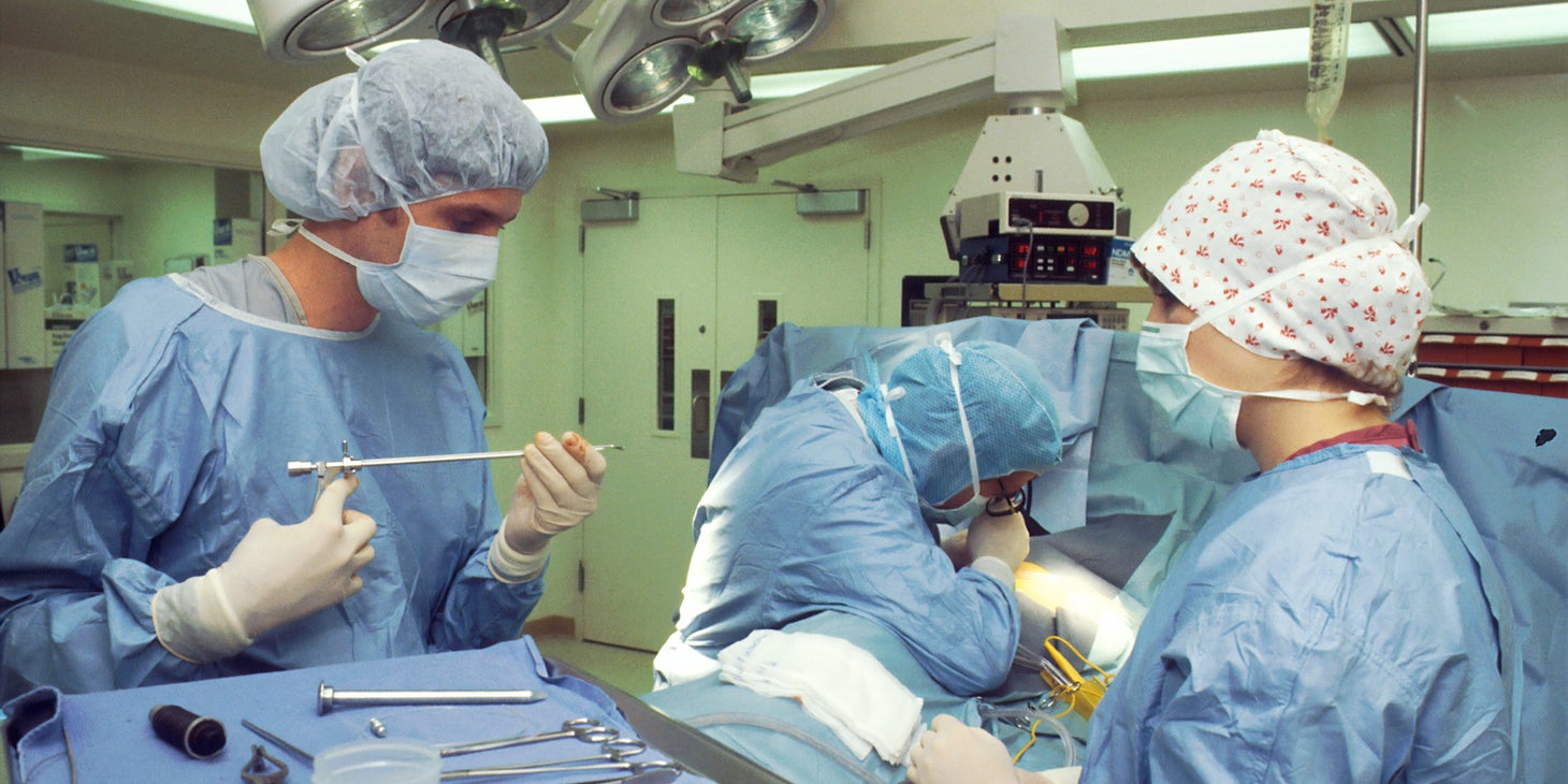 Surgical Technologist carefully holds surgical equipment during an operation