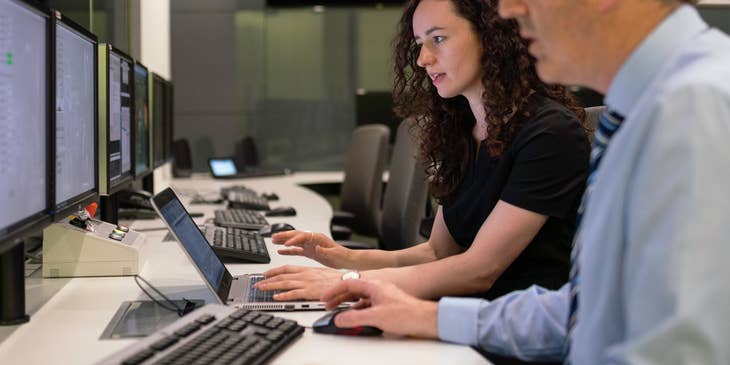 Systems Analyst working with a colleague evaluating current IT systems while preparing for a software upgrade