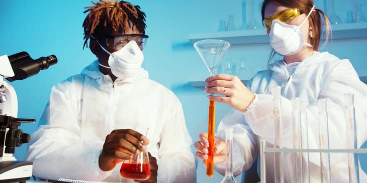 Toxicologist studies new toxin specimen and its effect in a laboratory with a colleague in a protective suit
