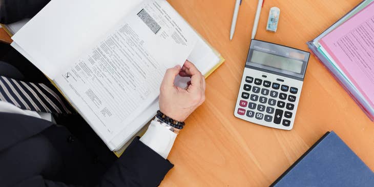 Account Officer holding book with calculator on table