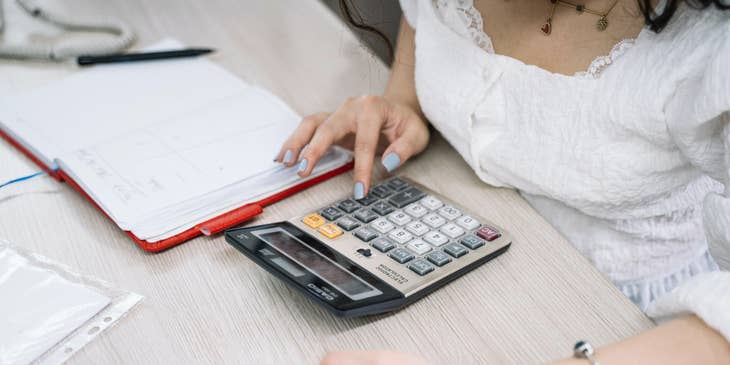 Accounting Intern holding a smartphone while using the calculator