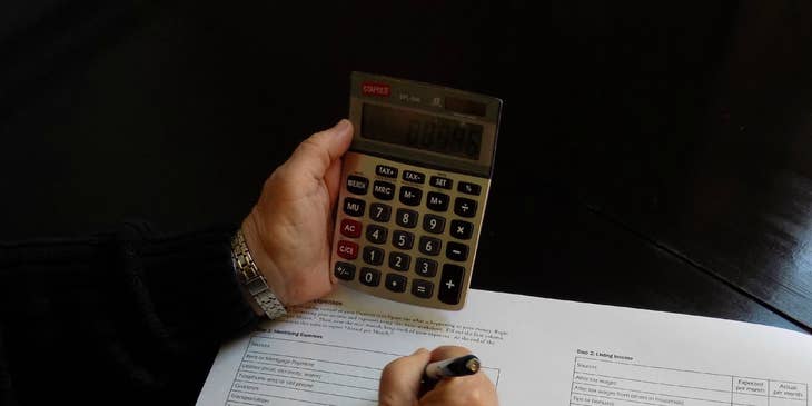 Accounting Officer writing down on a paper while holding a calculator