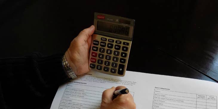 Accounting Officer writing down on a paper while holding a calculator