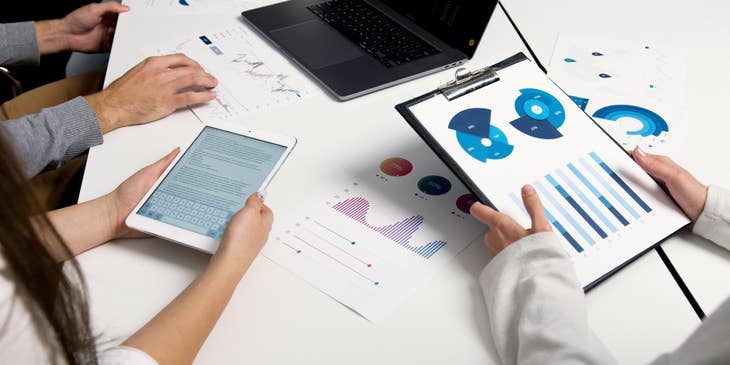 An Actuary wearing white long sleeves presenting data charts to the team.