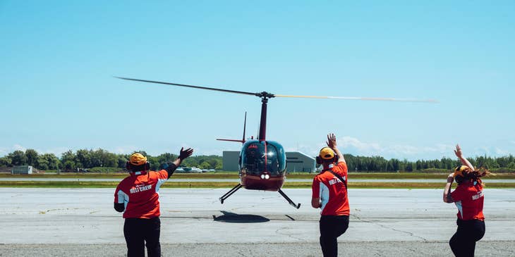 A Group of Air Traffic Controllers assisting a pilot in a helicopter upon arrival.