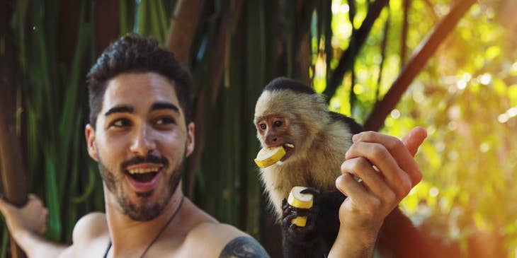 Anthropologist feeding a capuchin on his expedition to study the native animals of a certain island