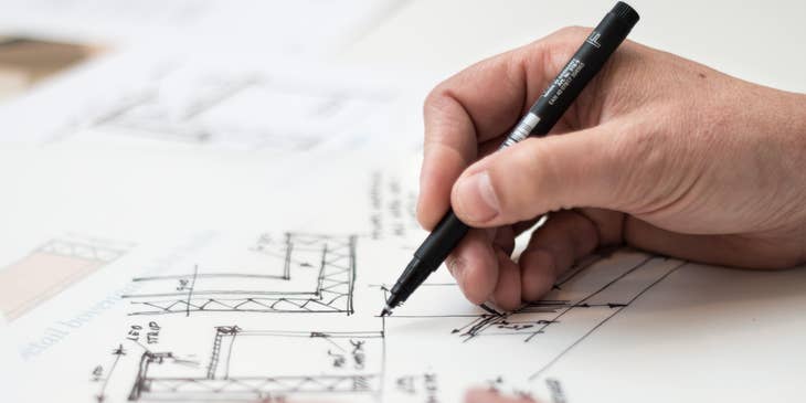 Architectural Engineer holding a black pen and revising the floor plan of a building