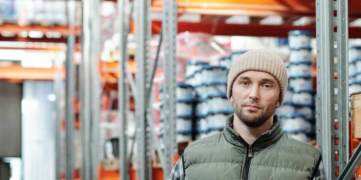 An Assistant Production Manager holding a tablet in a production warehouse ensuring production is within schedule.