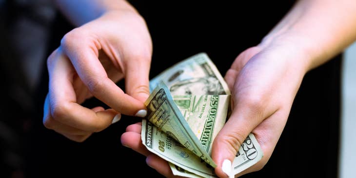 Bank Teller counting twenty dollar bills.