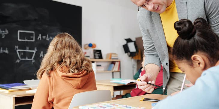 An after-school teacher helping a student with a math problem.