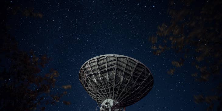 A radio telescope against the starry night sky.
