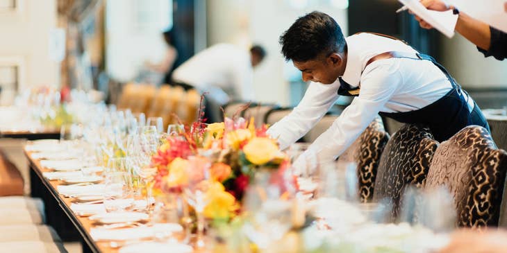 A banquet server prepares a banquet table