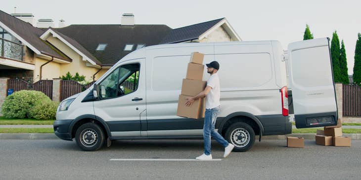 Un repartidor llevando paquetes a un punto de entrega designado, desde su camión de mensajería.