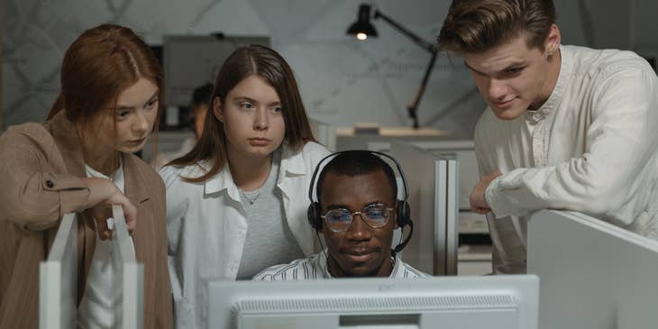 A call center trainer showing co-workers an important document on a computer,