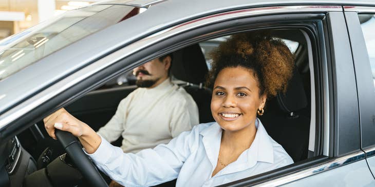 Una donna sorridente al volante di una macchina aziendale.