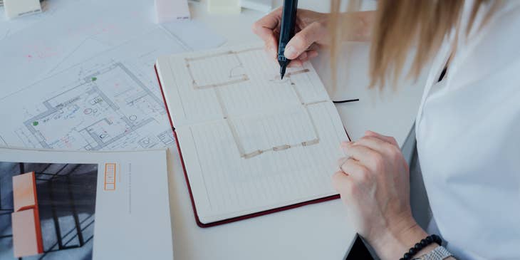 A design drafter sketching a design in a notebook.