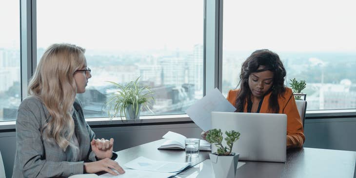 Development Coordinator checking files while listening to colleague planning an event