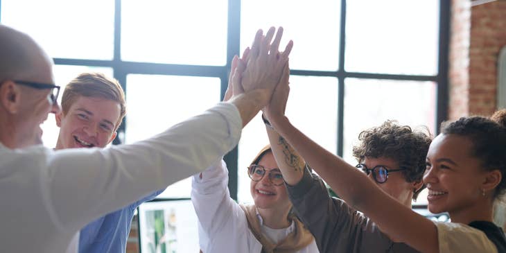 Un grupo de personas alzando sus manos en una actividad para mejorar el trabajo en equipo.