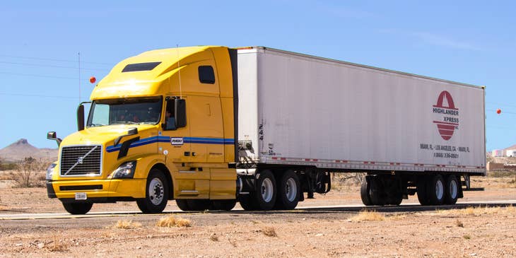 A yellow and white lorry on the road.