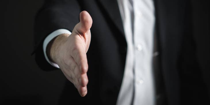 A man making a job offer and extending a hand to shake.