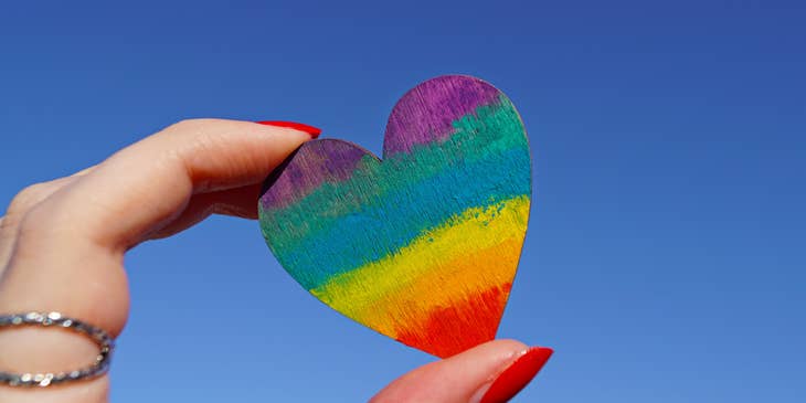 A person holding a multicolored heart-shaped card.
