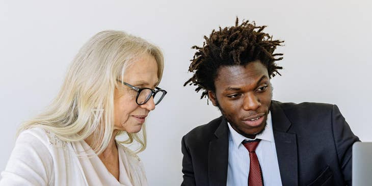 A loan specialist sitting beside a woman in a white shirt discussing a loan option.