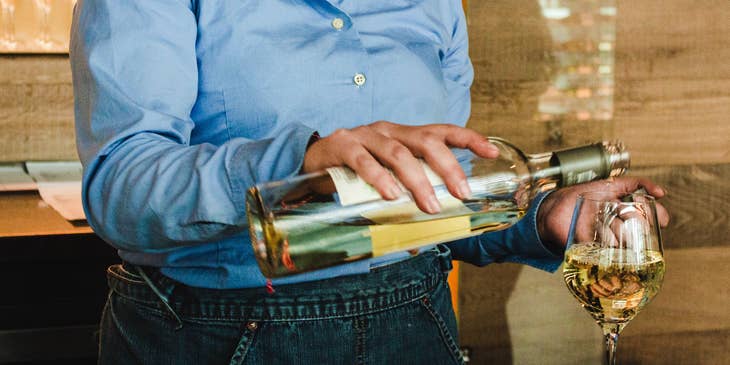 Una mujer sirviendo vino en un vaso.