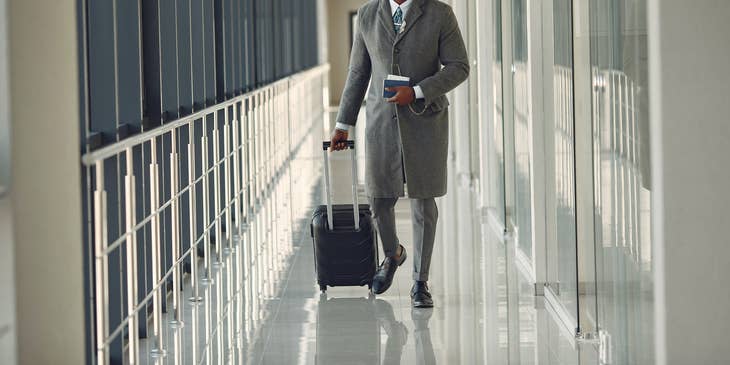 Un hombre con equipaje de ruedas en un aeropuerto.