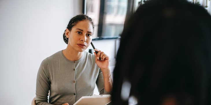 A protective services worker taking a statement from a person sitting at a table.