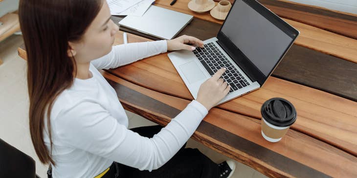 A senior internal auditor typing on a laptop at their desk.