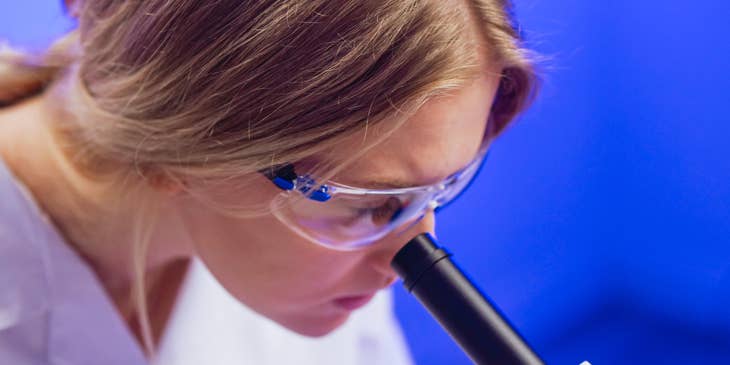 A social science research assistant looking into a microscope.